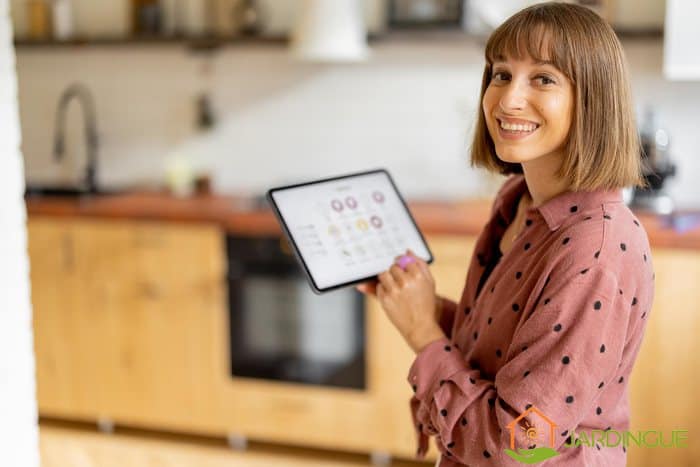 jeune femme contrôle l'alarme de sa maison depuis une tablette tactille